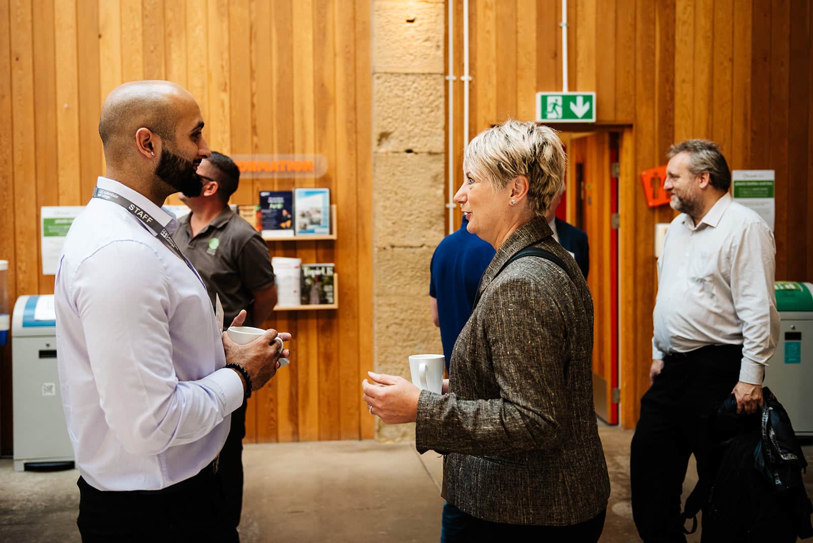 Group of people speaking to each other holding mugs of coffee or tea at EWIC.