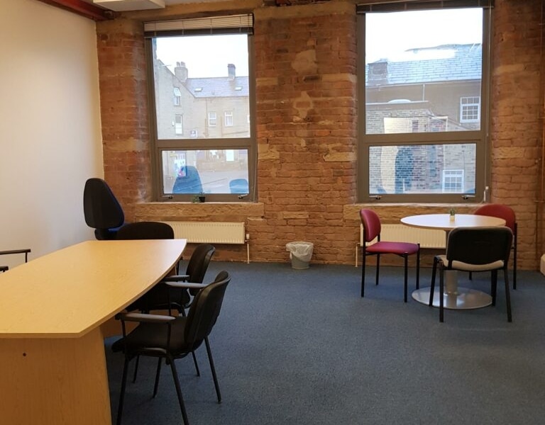 Interior of one of the offices to rent at EWIC. It is a medium sized room with a desk and small round table to the side.